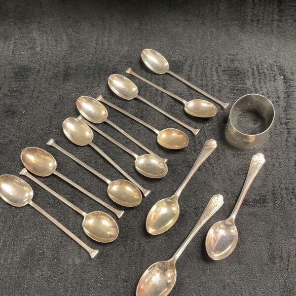 Hallmarked sterling silver spoons and a napkin ring on display.