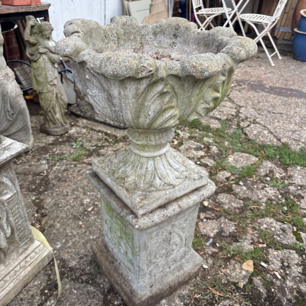 Weathered stone garden urn on a plinth, vintage garden decor.