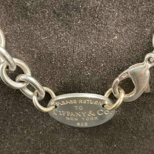 Close-up of Tiffany & Co. necklace tag with "Return to Tiffany" inscription.