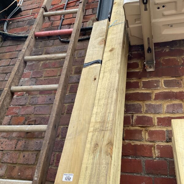 Three bundles of 10ft timber leaning against a brick wall.