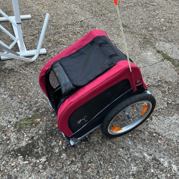 Red Trixie pet bike trailer attached to a bicycle.