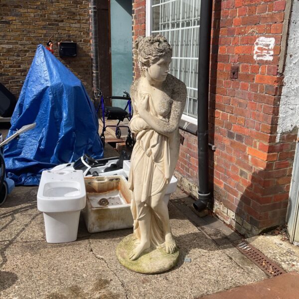Large stone effect Venus statue in a garden setting.