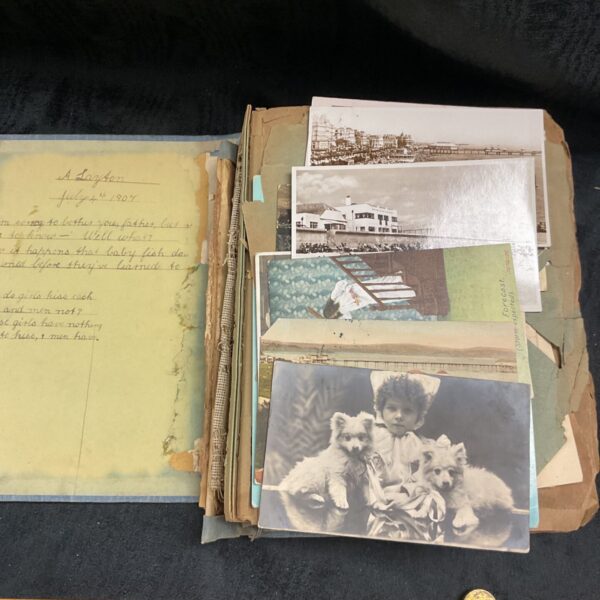 Victorian postcard album open to first pages with handwritten notes.