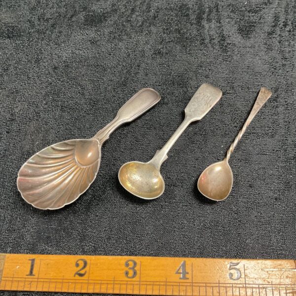 Group of three antique Victorian silver spoons on dark background.