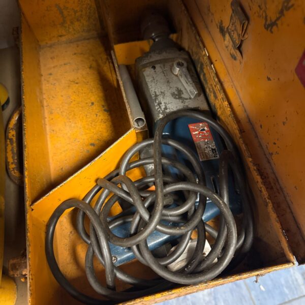 Vintage AEG drill in metal toolbox, classic power tool.
