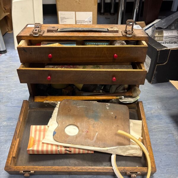 Vintage wooden artist's travel case filled with antique painting supplies.