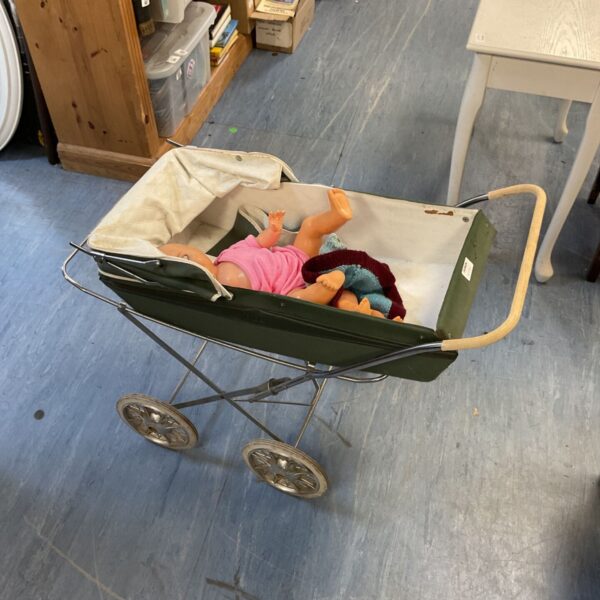 Vintage baby doll pram with dolls inside, a collectible toy.
