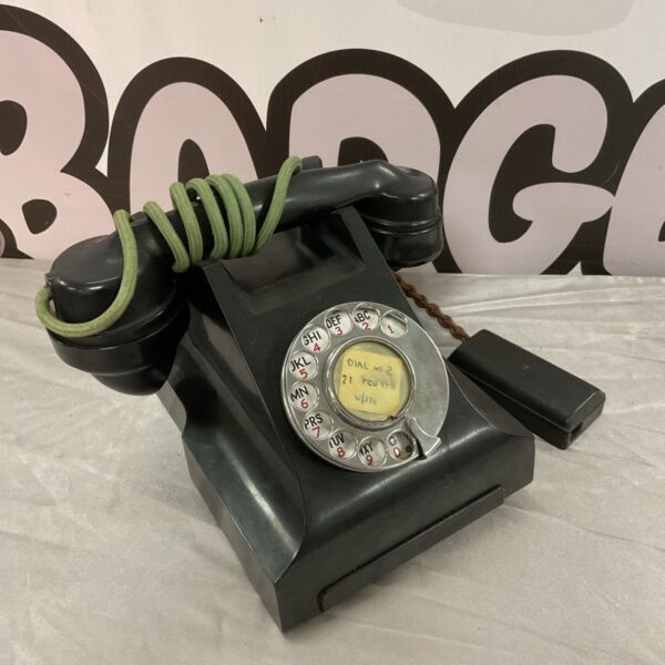 Vintage black Bakelite rotary telephone with coiled cord.
