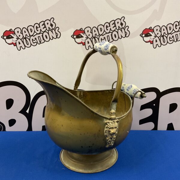 Vintage brass helmet coal scuttle with blue and white ceramic handles.