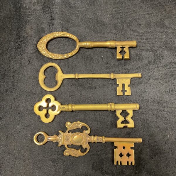 Lot of four vintage brass keys with ornate designs.