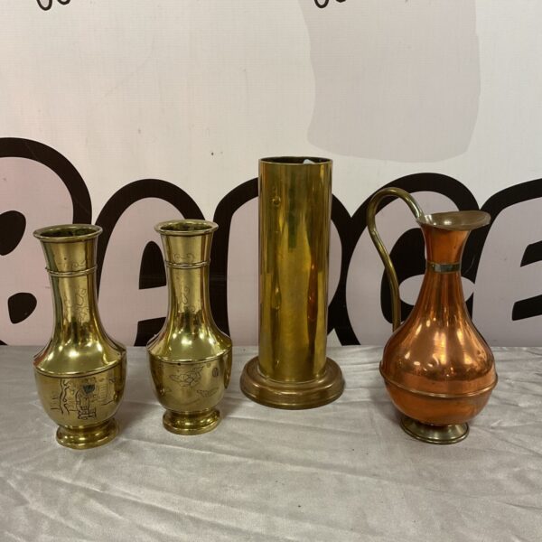 Vintage brass vases and a small copper pitcher on display.