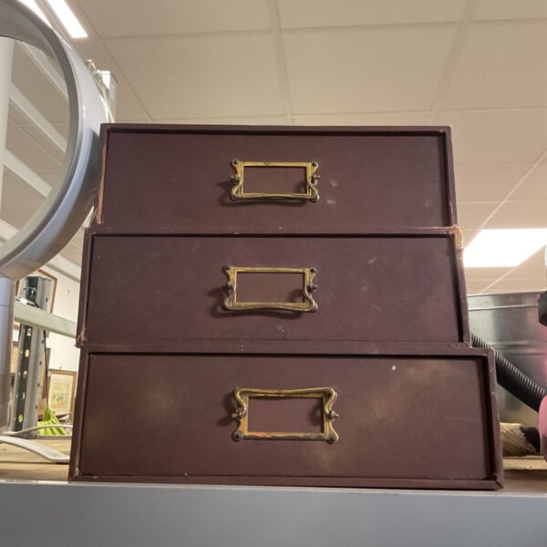 Stack of three vintage brown drawers for storage.