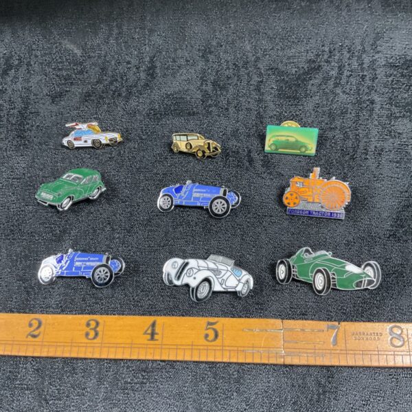 Lot of vintage car enamel pin badges, classic automotive collectibles.