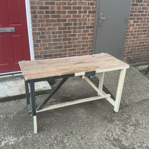 Vintage carpenter’s workbench with a worn wood top and metal legs.