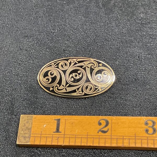 Close-up of vintage Celtic brooch with intricate enamel design.