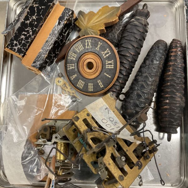 Tray of vintage cuckoo clock parts for repair or collection.