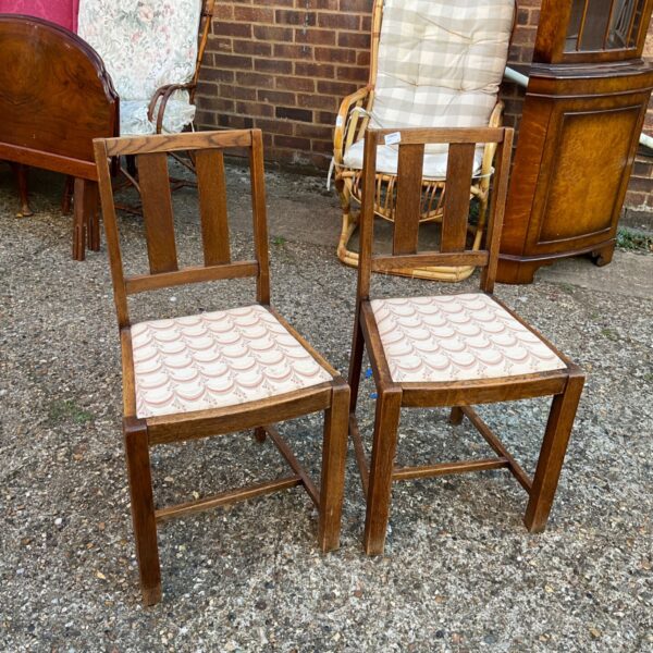 Pair of vintage wooden dining chairs with upholstered seats.
