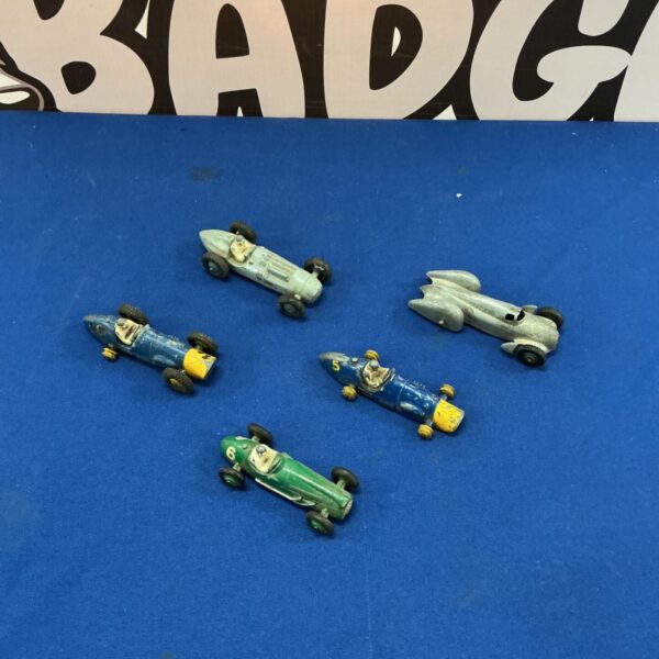 Vintage Dinky diecast racing cars on a blue surface.