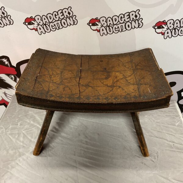 Side view of a vintage 1929 carved wooden footstool.