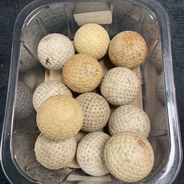 Tray of vintage golf balls, antique golf collectibles for display.