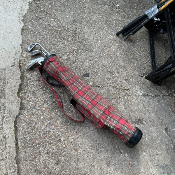 Vintage golf clubs in a red tartan bag, classic sporting equipment.