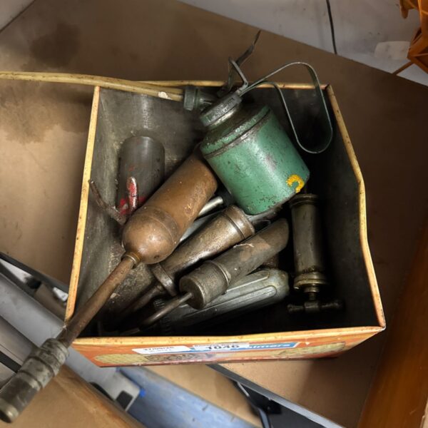 Vintage grease guns and oil can in a box, antique workshop tools.