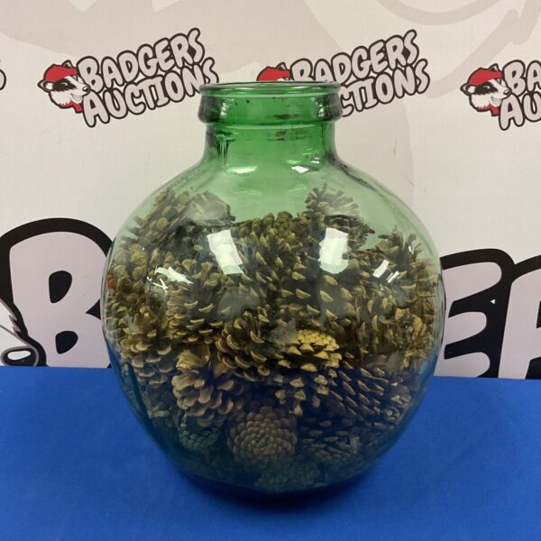Vintage green glass terrarium filled with pine cones for display.