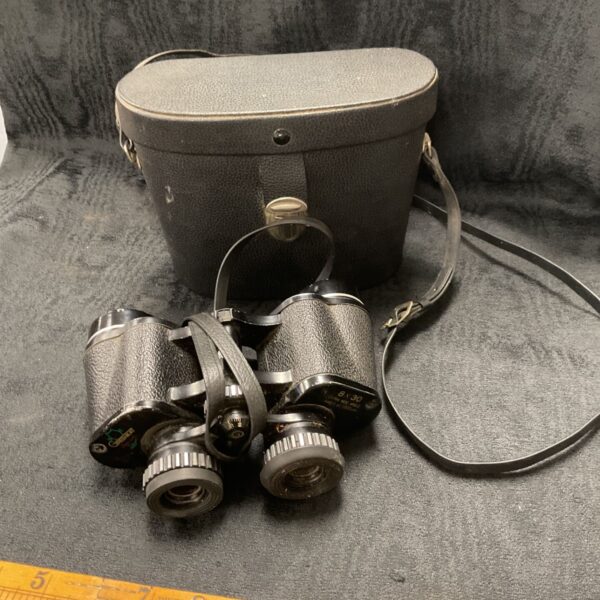 Vintage Greenkat 8x30 binoculars with original case displayed on a ruler.