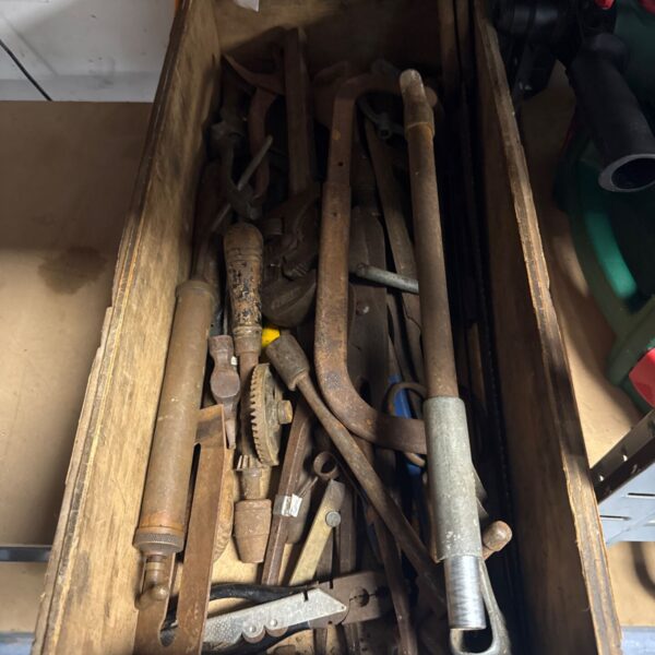 Vintage hand tools in a wooden tray, rusty metal workshop collection.