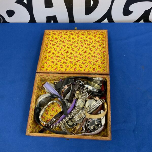 Open vintage jewellery box filled with watches and jewellery.