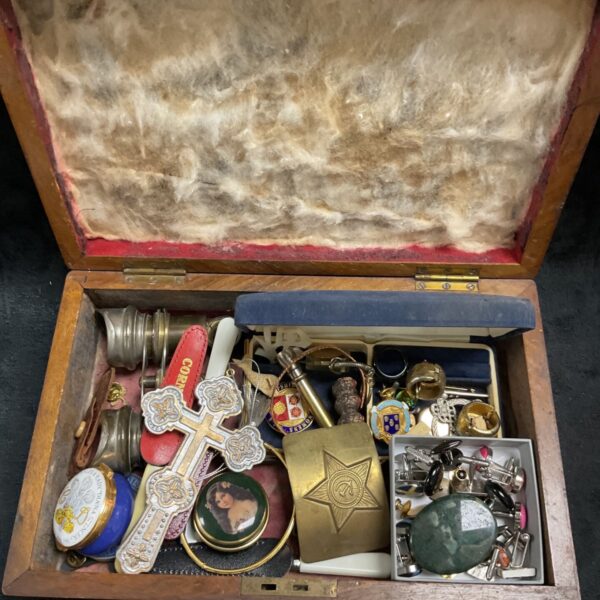Vintage jewellery and collectibles box with brooches and pendants.