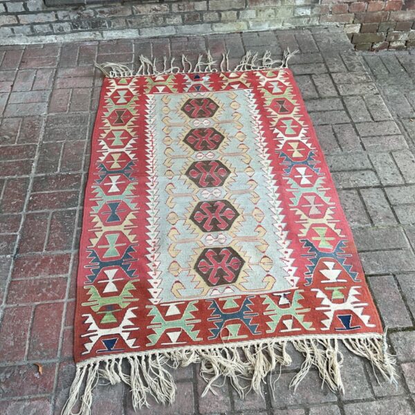 Vintage Kilim rug with red geometric border and hexagonal medallions.