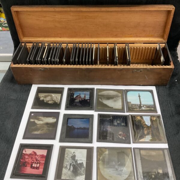 Vintage magic lantern slides displayed in a wooden tray.