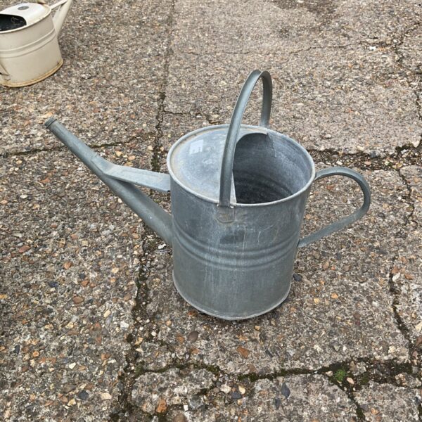 Vintage metal watering can with a patina, ideal for garden use.