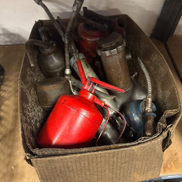 Vintage oil cans and tools in a cardboard box.