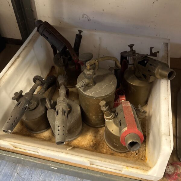 Selection of vintage paraffin blowtorches in a plastic container.