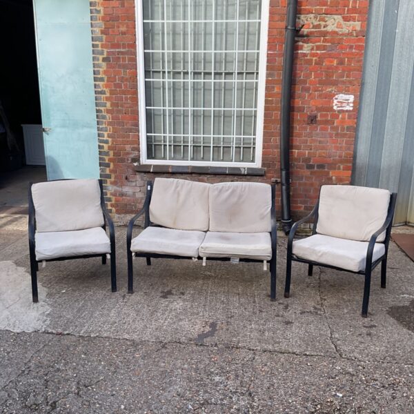 Vintage patio sofa set with two chairs in a garden setting.