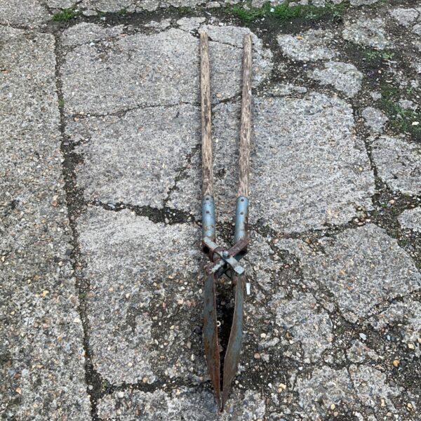Antique post digging spade with wooden handles and rusted metal blade.