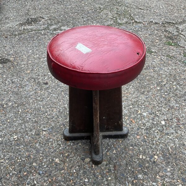 Vintage red counter stool with oak base for diner or kitchen.