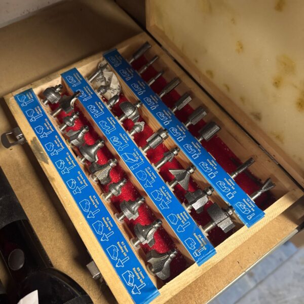 Vintage router bit set in wooden case with various bits.