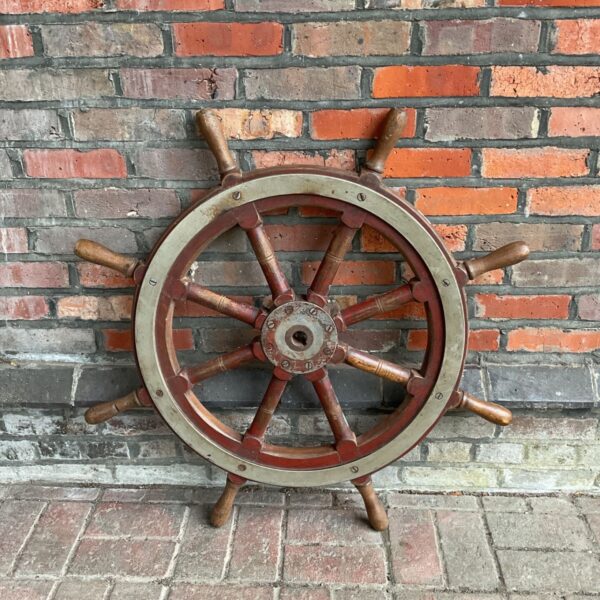 Vintage wooden ships wheel with metal rim, nautical decor.
