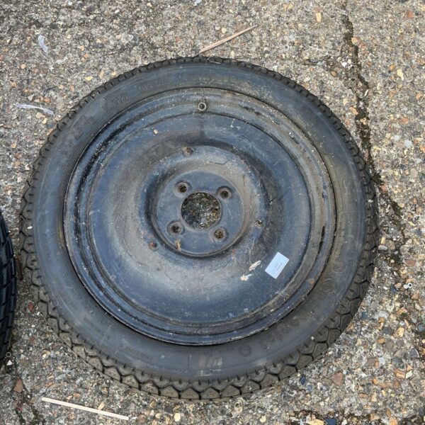 Vintage spare wheel with steel rim and worn tyre for classic cars.