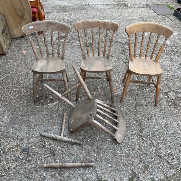 Vintage light oak spindle back dining chairs awaiting restoration.