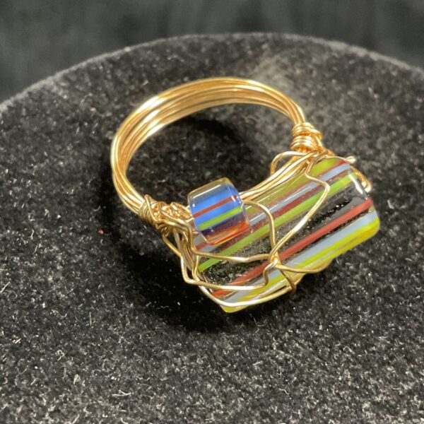 Close-up of vintage striped glass ring with gold wire wrap.