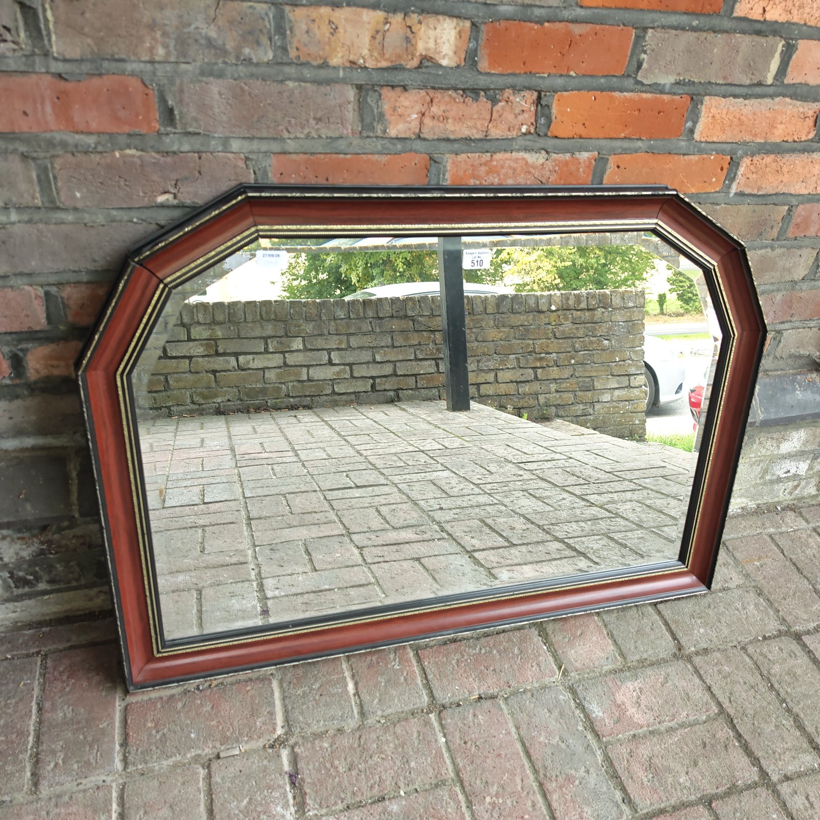 Ornate vintage style wall mirror with reddish-brown frame.