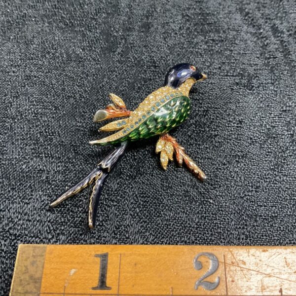 Close-up of vintage swallow brooch with green enamel and rhinestones.