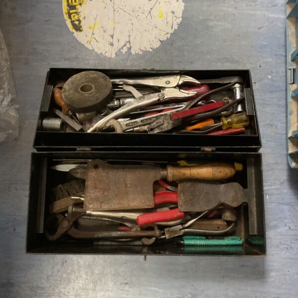 Vintage black metal toolbox filled with various hand tools.