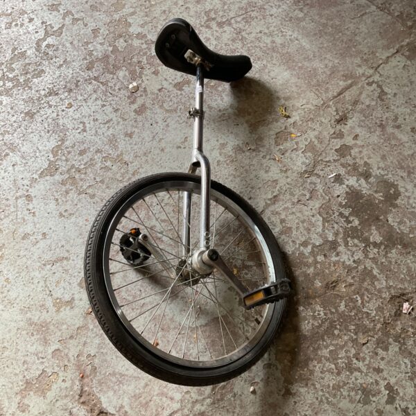 Silver vintage unicycle with black tire and seat.