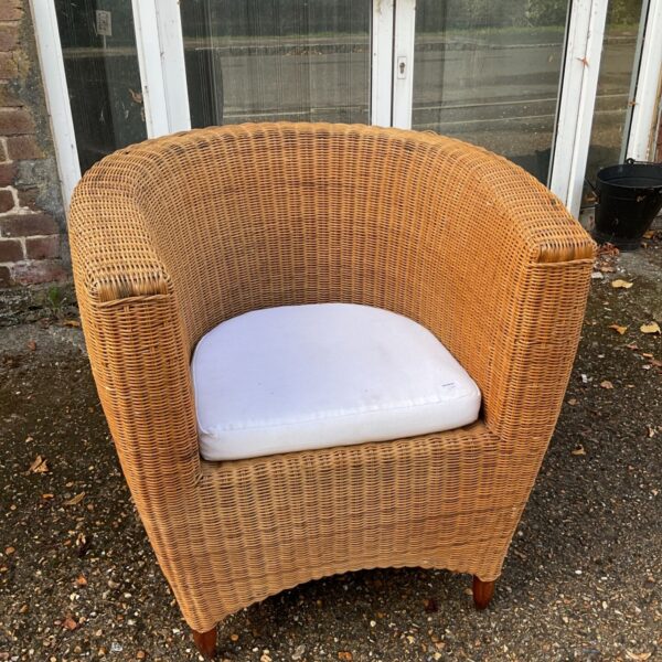 Vintage wicker armchair with mahogany feet, a stylish seating option.