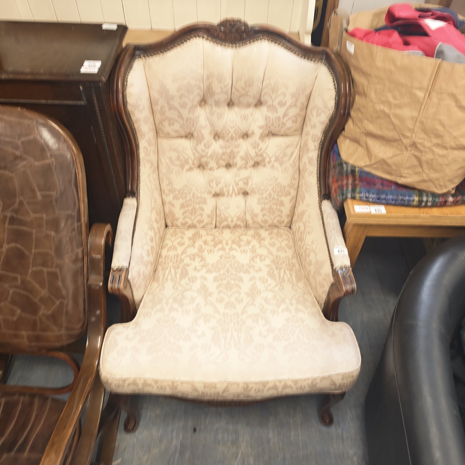 Vintage wingback armchair with cream damask upholstery and carved wood.